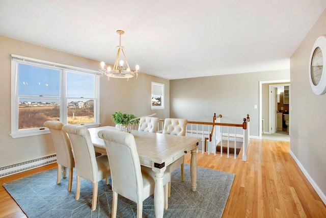 dining space featuring a chandelier, light wood-type flooring, and a baseboard heating unit