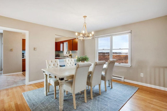 dining area featuring light wood-type flooring, baseboard heating, and a chandelier