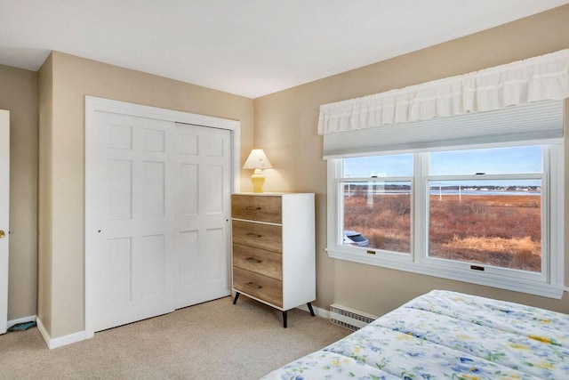 bedroom with a closet, light carpet, and a baseboard radiator