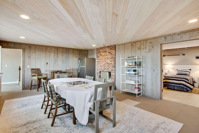 dining space with wood walls, wooden ceiling, and a brick fireplace