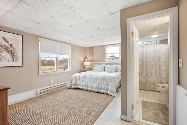 bedroom with connected bathroom, a baseboard radiator, and a paneled ceiling