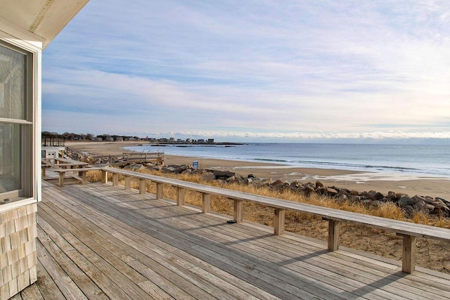 wooden deck featuring a beach view and a water view