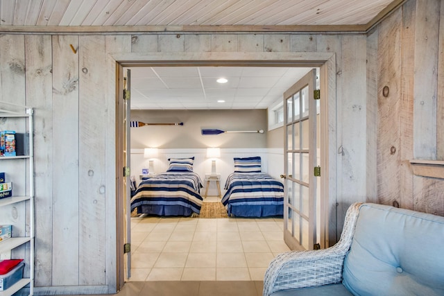 bedroom featuring light tile patterned floors and wooden walls