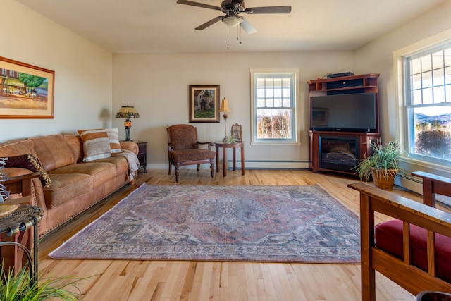 living room with ceiling fan, light hardwood / wood-style floors, and a baseboard heating unit