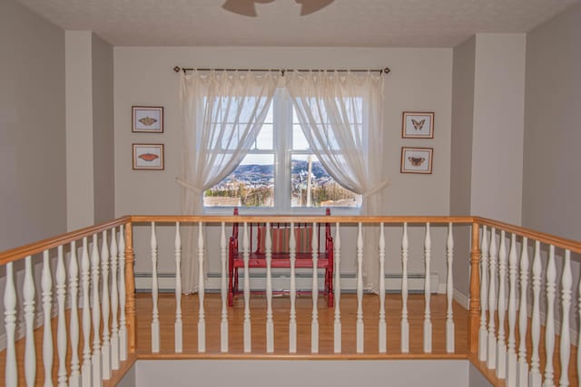 stairway with baseboard heating, a textured ceiling, and hardwood / wood-style floors