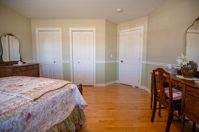 bedroom with two closets and light hardwood / wood-style floors