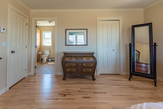 sitting room featuring light wood-type flooring, ornamental molding, and a baseboard heating unit