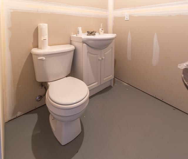 bathroom featuring toilet, vanity, and concrete flooring