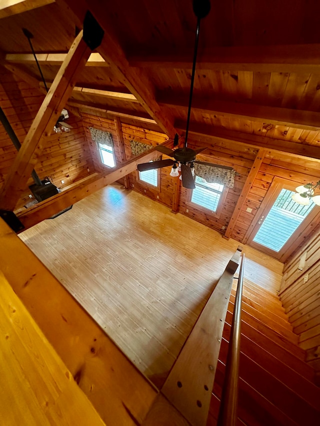 room details with wood walls, a skylight, beamed ceiling, ceiling fan, and hardwood / wood-style floors