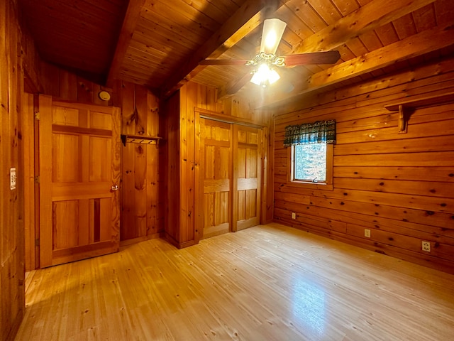 unfurnished bedroom featuring wooden walls, beam ceiling, and light hardwood / wood-style flooring