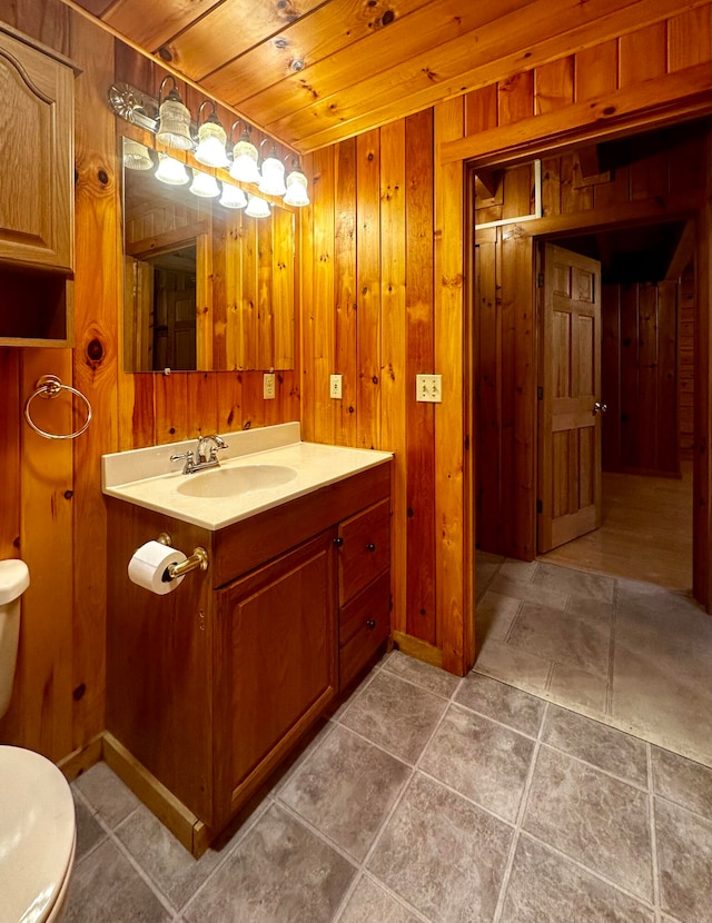 bathroom with vanity, wood ceiling, wood walls, tile patterned floors, and toilet