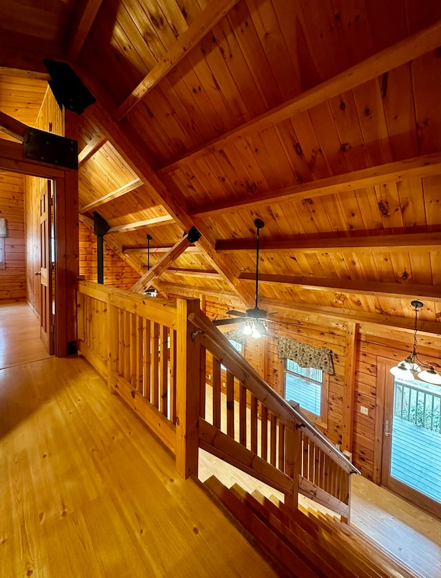 corridor featuring vaulted ceiling with beams, wood walls, wooden ceiling, and light hardwood / wood-style floors