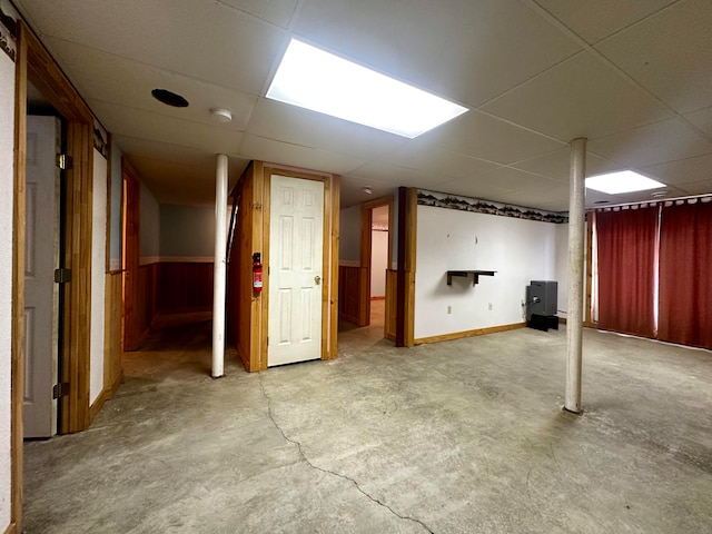 basement with a drop ceiling and wooden walls