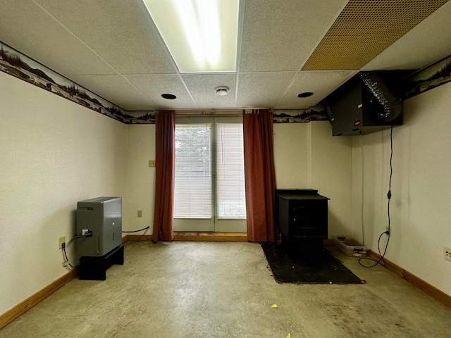 basement with a drop ceiling and a wood stove