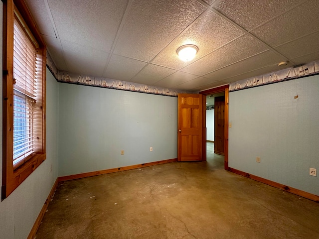 empty room featuring a paneled ceiling and concrete floors