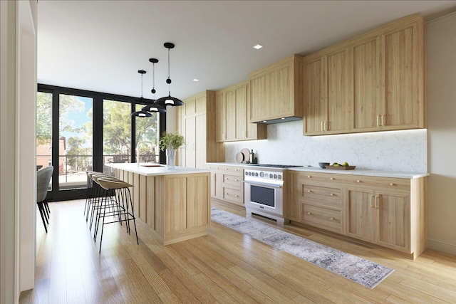 kitchen with light brown cabinets, an island with sink, light wood-type flooring, and pendant lighting