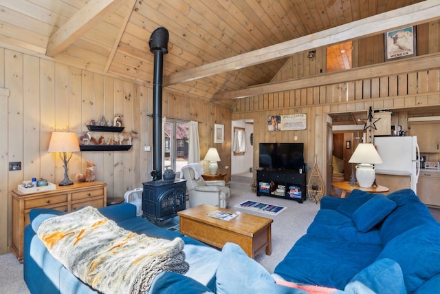 carpeted living room with a wood stove, wood walls, vaulted ceiling with beams, and wooden ceiling