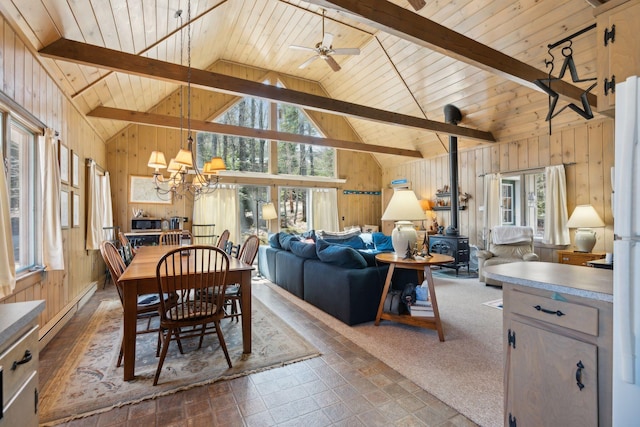 tiled dining area featuring beamed ceiling, plenty of natural light, wooden walls, and a wood stove