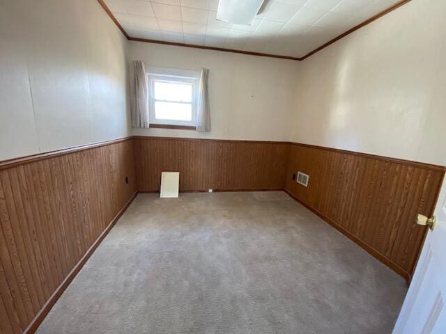 empty room with crown molding and light carpet