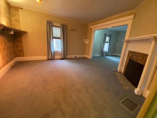 unfurnished living room featuring ornamental molding, dark carpet, and a high end fireplace