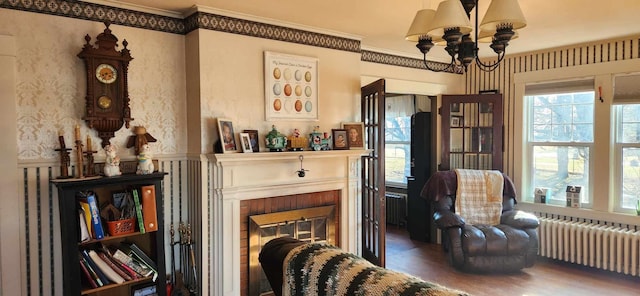 sitting room featuring ornamental molding, hardwood / wood-style floors, radiator heating unit, and a chandelier