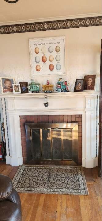 interior details with a brick fireplace, hardwood / wood-style flooring, and ornamental molding