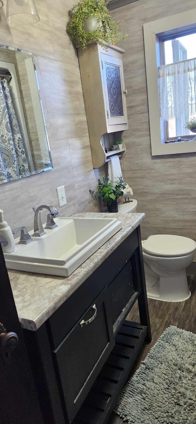 bathroom featuring vanity, tile walls, toilet, and hardwood / wood-style flooring