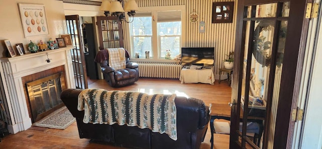 living room featuring radiator, hardwood / wood-style floors, and a chandelier