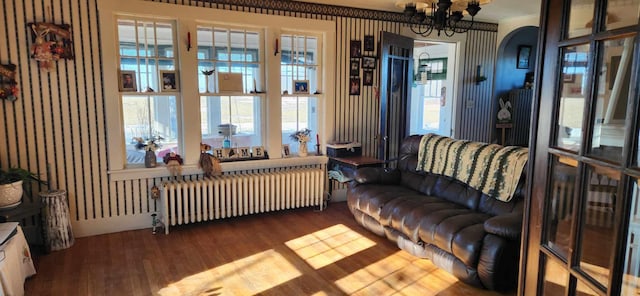 living room featuring wood-type flooring, an inviting chandelier, ornamental molding, and radiator heating unit