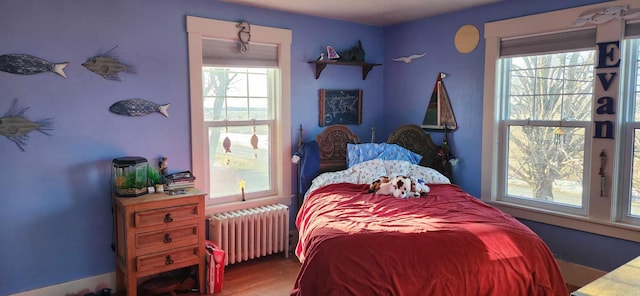 bedroom featuring multiple windows, radiator, and hardwood / wood-style floors