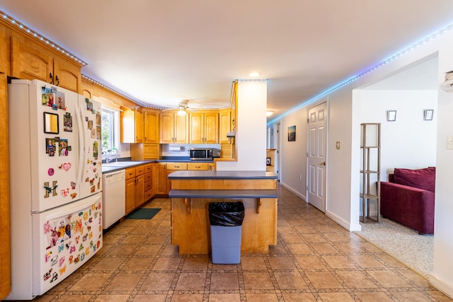 kitchen with a kitchen island, white appliances, crown molding, sink, and light tile floors