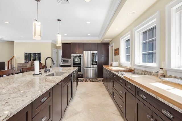 kitchen featuring appliances with stainless steel finishes, sink, hanging light fixtures, crown molding, and dark brown cabinets