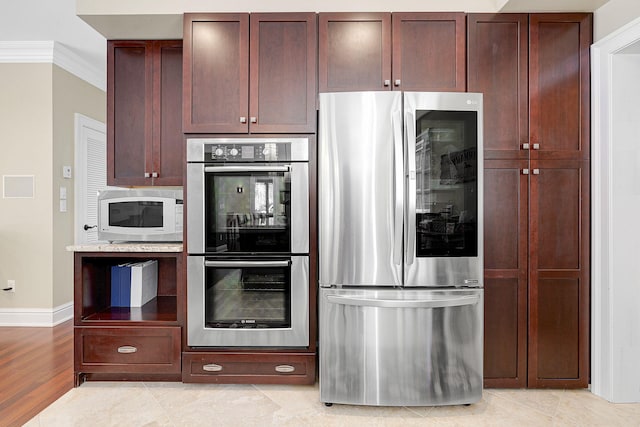 kitchen featuring light tile patterned floors, ornamental molding, and appliances with stainless steel finishes