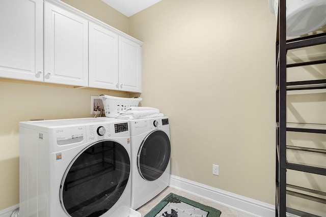 clothes washing area with independent washer and dryer, light tile patterned floors, and cabinets