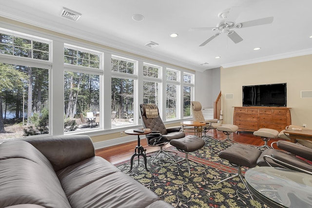 living room with crown molding, wood-type flooring, and ceiling fan