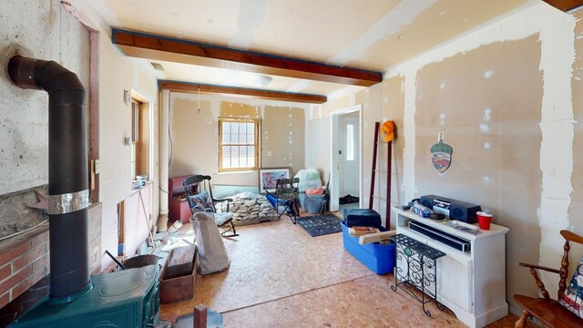 misc room featuring beamed ceiling and a wood stove