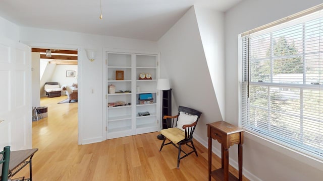 living area featuring beam ceiling and light wood-type flooring