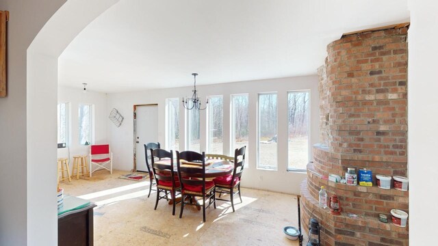 dining room with brick wall, a healthy amount of sunlight, and a chandelier