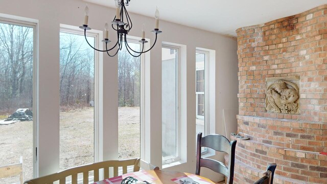 dining space with a notable chandelier and brick wall