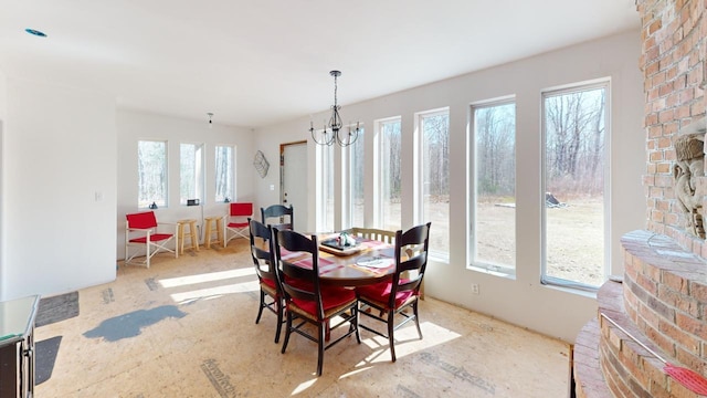 dining area with brick wall, a wealth of natural light, and an inviting chandelier