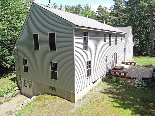 view of property exterior with a deck and a lawn