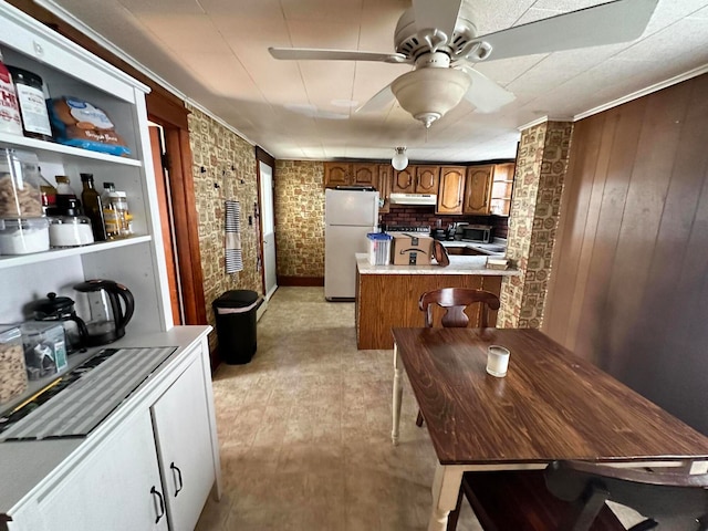 kitchen with ceiling fan, white fridge, stove, brick wall, and crown molding