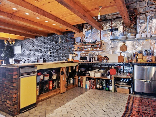 interior space featuring a notable chandelier, brick wall, refrigerator, and beamed ceiling