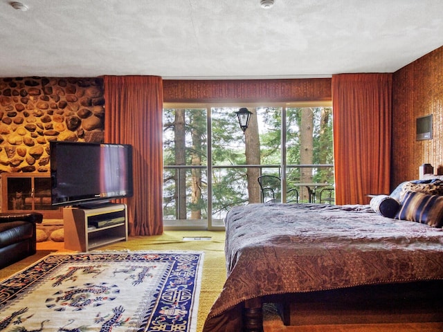 bedroom with a textured ceiling, wooden walls, and multiple windows