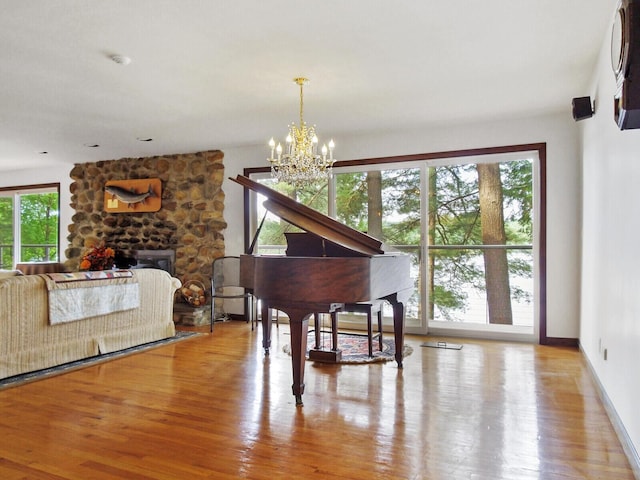 miscellaneous room featuring light wood-type flooring, an inviting chandelier, and a fireplace