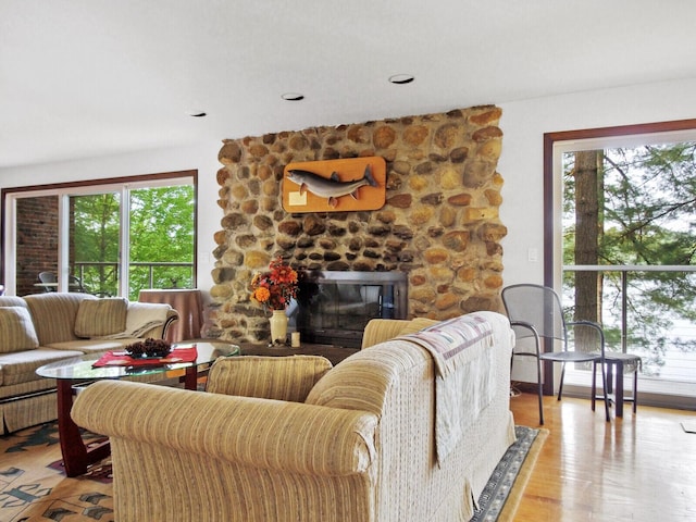 living room featuring plenty of natural light, a stone fireplace, and light hardwood / wood-style floors