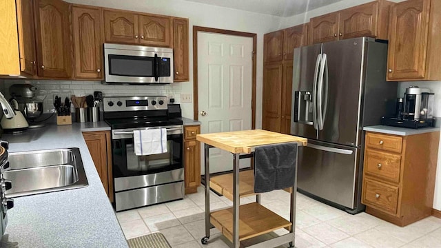 kitchen featuring backsplash, sink, stainless steel appliances, and light tile floors