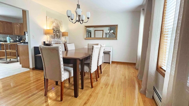 dining room with a chandelier, a baseboard radiator, and light wood-type flooring