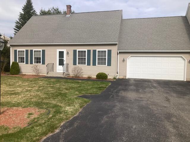 cape cod home featuring a front lawn and a garage