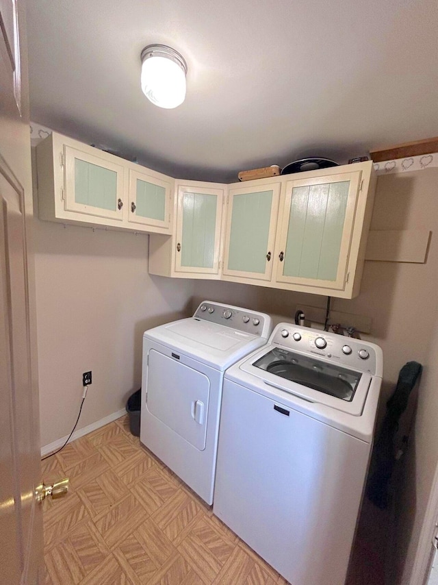 laundry room with cabinets, light parquet flooring, and washer and clothes dryer